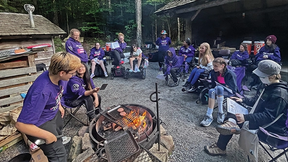 Young women cooking burgers around a campfire