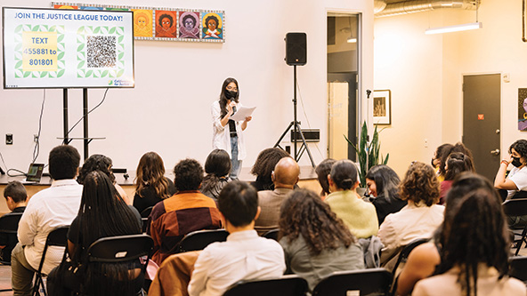 young person on stage with microphone reading a report to audience