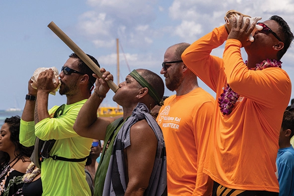 Men blowing into conch shells