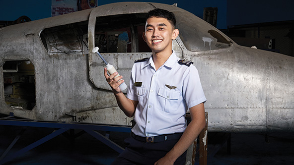 Man in aviation uniform standing in front of an airplane holding his invention, Pili Seal