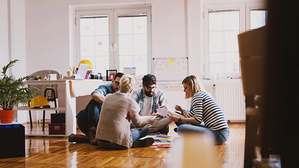 Creative team is trying to develop new ideas while sitting on a floor in a inspiring room.