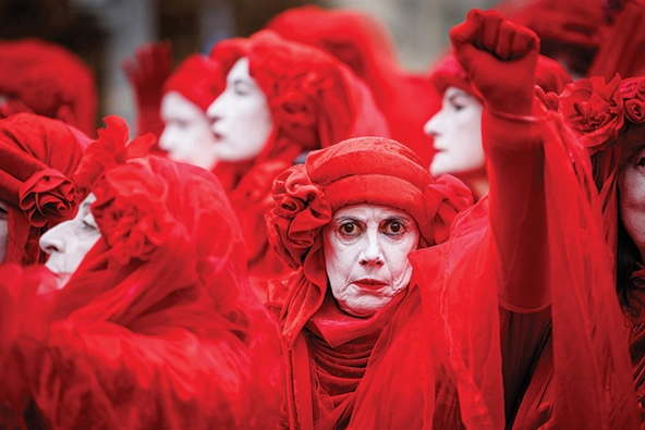 protestors with white painted faces and red costumes