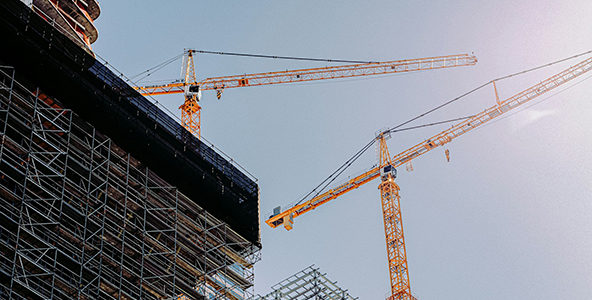 Photo of two construction cranes above high-rise apartment buildings
